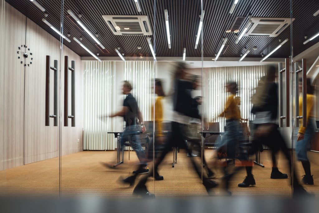 Blurred figures of people walking through a modern office